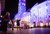 Piazza notturna con proiezioni natalizie luminose su edifici e persone