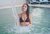 Donna con bikini nero in piscina con cascata di acqua