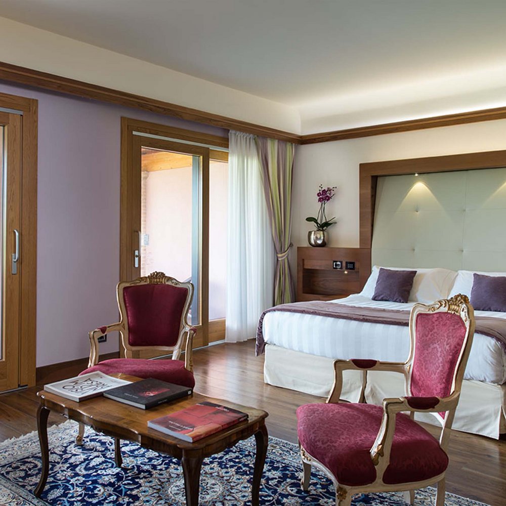 Das Hotel bei Assisi, das Sie gesucht haben Elegantes Schlafzimmer mit großem Bett, roten Sesseln und Blick auf die Terrasse