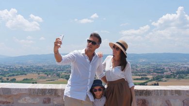 Vacanza vicino ad Assisi, Resort Hotel com Campo da Padel Tennis Bike Hotel 3 piscine campo da calcetto. Famiglia in vacanza che si fa un selfie con panorama rurale dietro