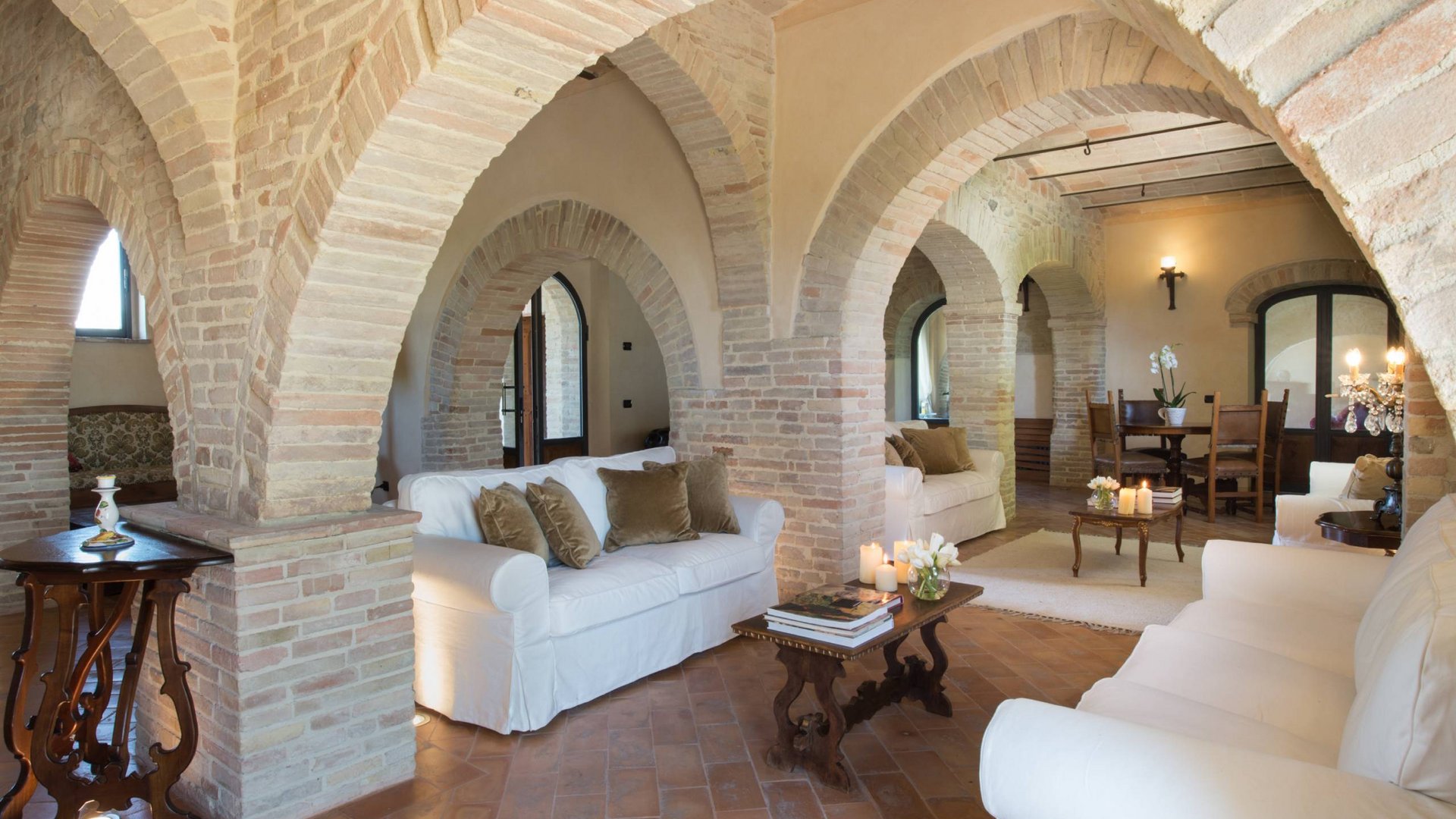 Villa ad Assisi con piscina privata, vacanze nel cuore dell'Umbria Salotto rustico con archi in mattoni e divani bianchi
