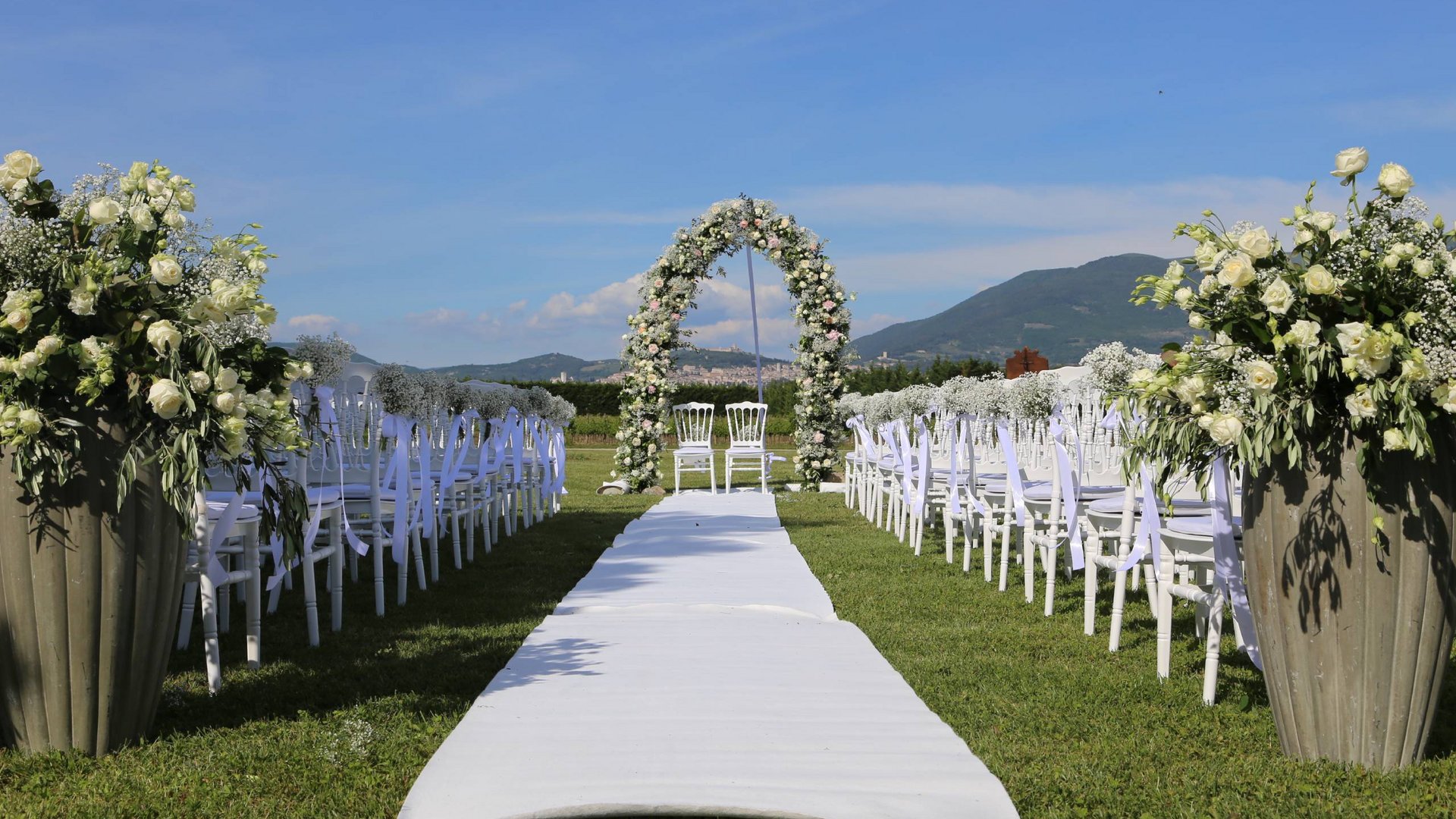 Your wedding location in Assisi Outdoor wedding setup with white chairs and floral arch