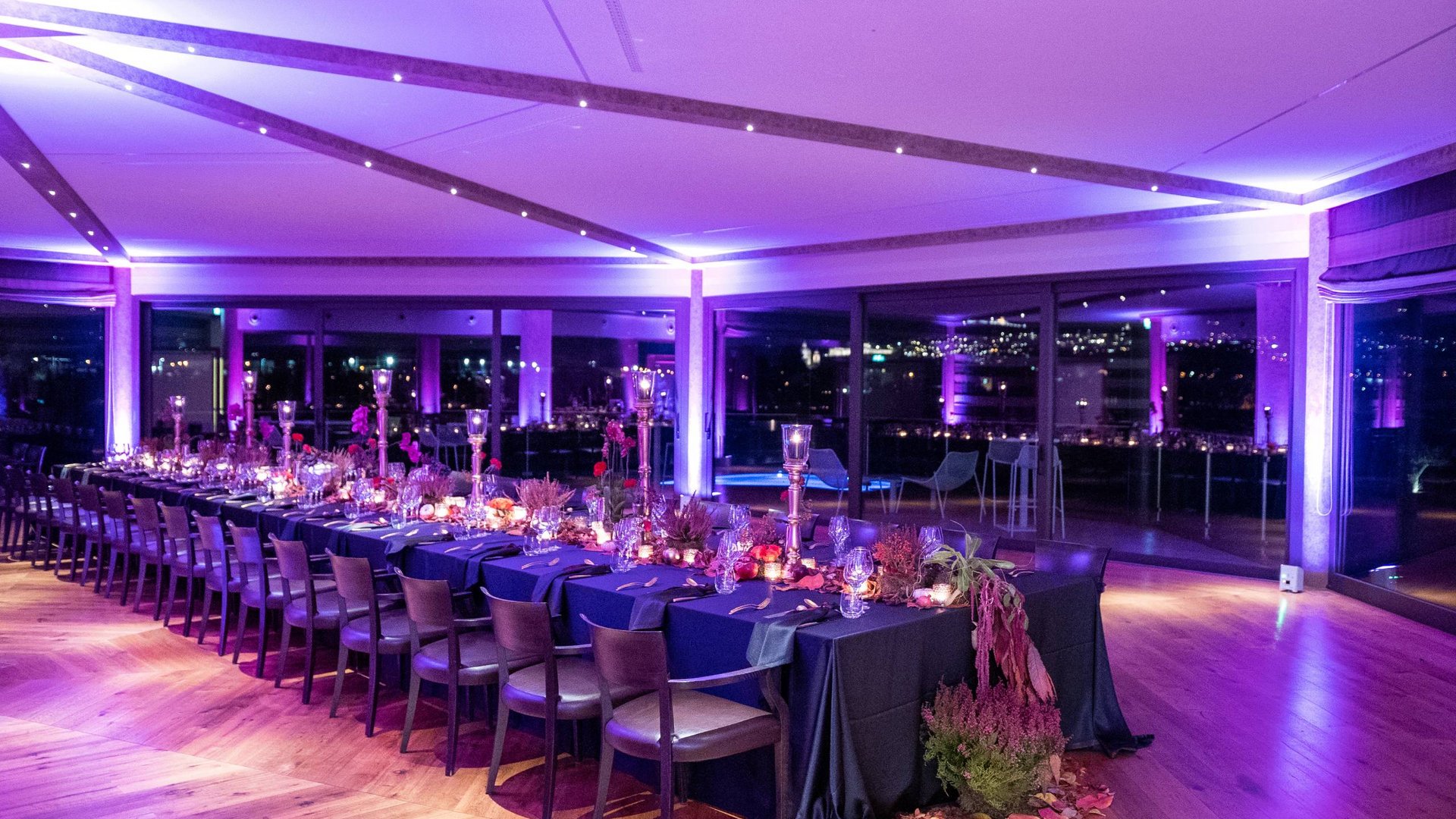Your wedding location in Assisi Long table set for elegant dinner with purple lighting and floral decorations