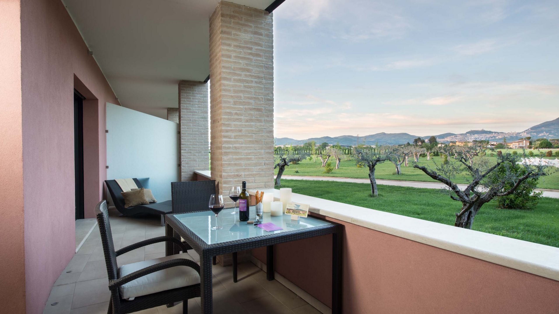 Un hotel a Santa Maria degli Angeli, Assisi? No, molto di più Terrazza con tavolo e due bicchieri di vino e vista su uliveto e colline