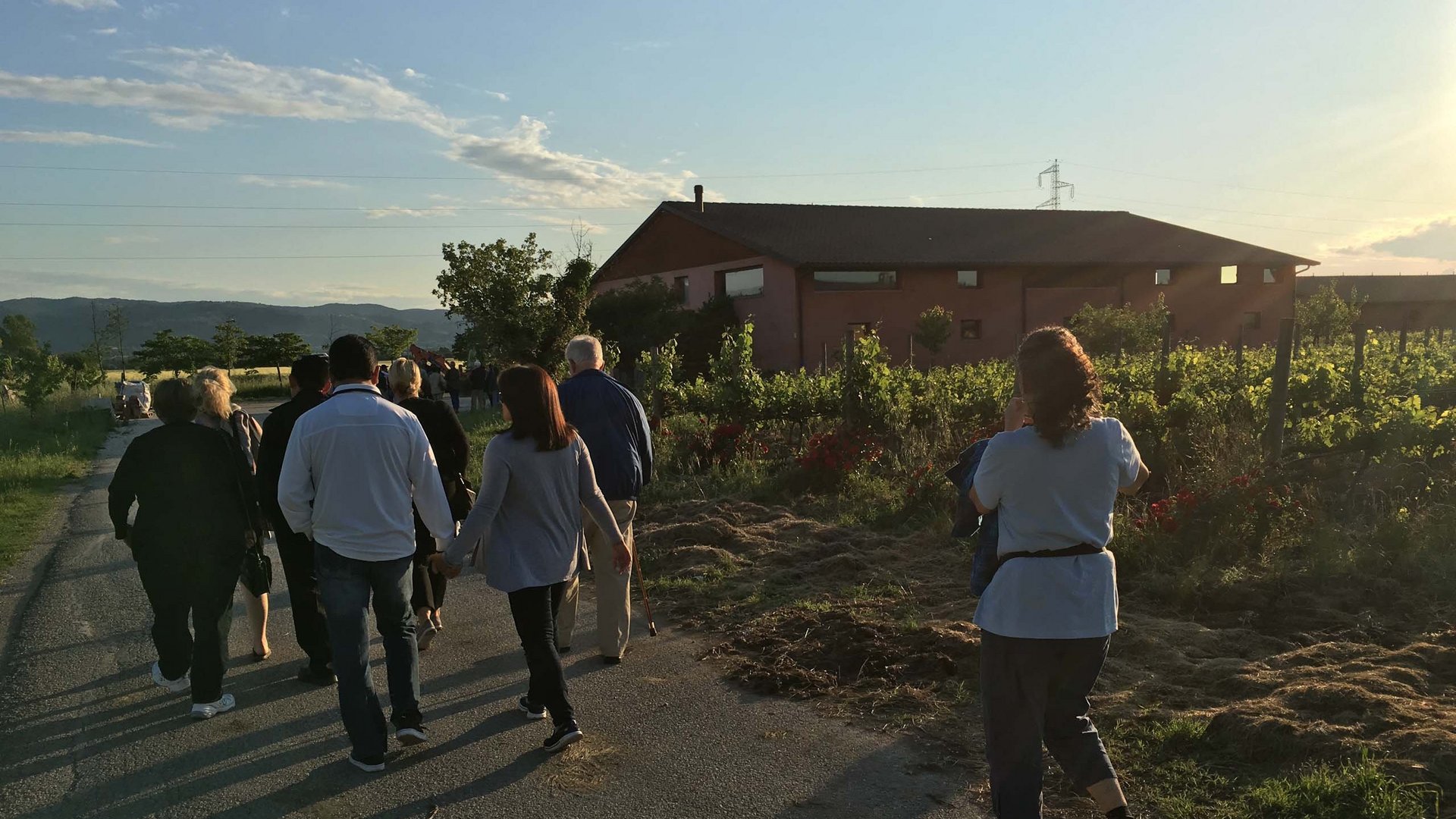 Team building in un hotel con centro benessere in Umbria Gruppo di persone che camminano su una strada vicino a una casa rurale al tramonto