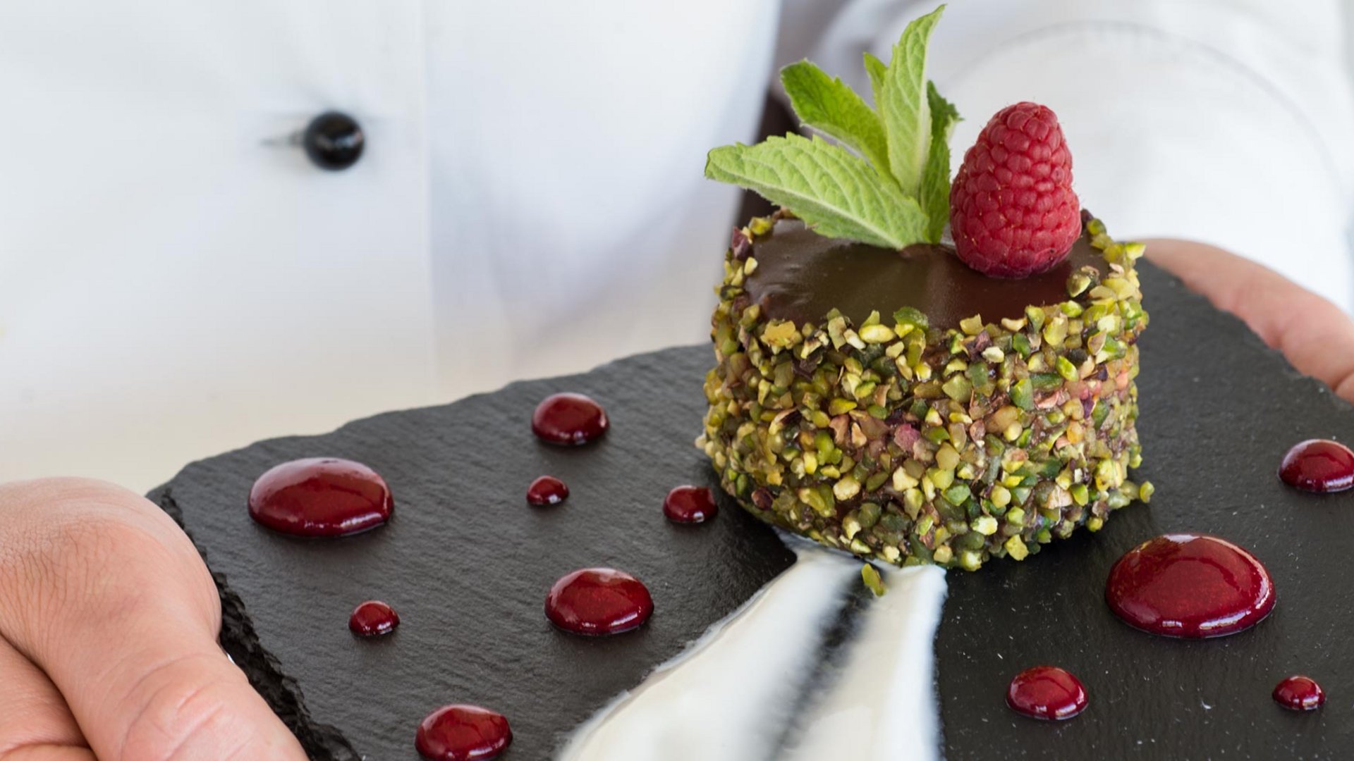 At Valle di Assisi, our restaurant, Recanto, awaits you. Dessert coated with pistachios, chocolate glaze, raspberry and mint