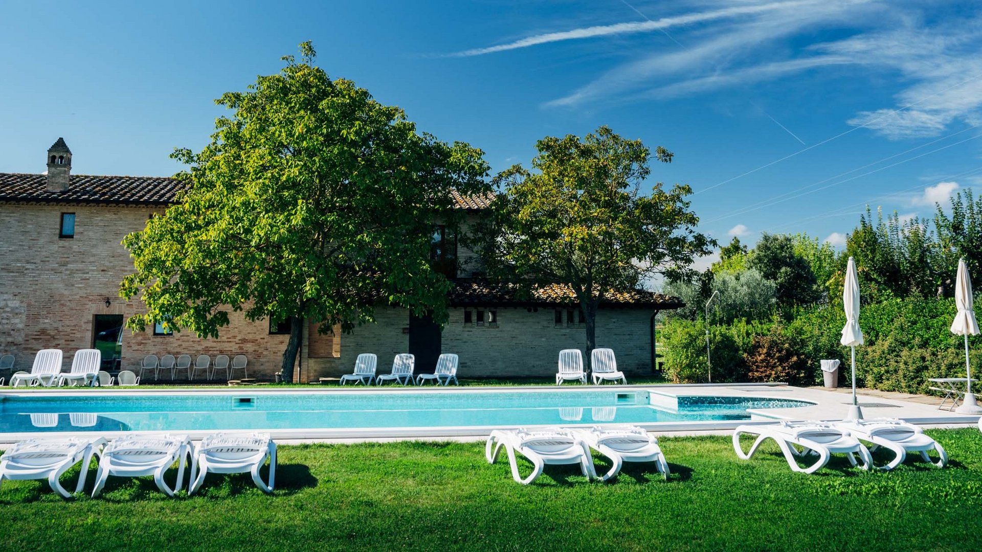 Villa ad Assisi con piscina privata, vacanze nel cuore dell'Umbria Piscina all'aperto con lettini e ombrelloni in un giardino soleggiato davanti a una casa