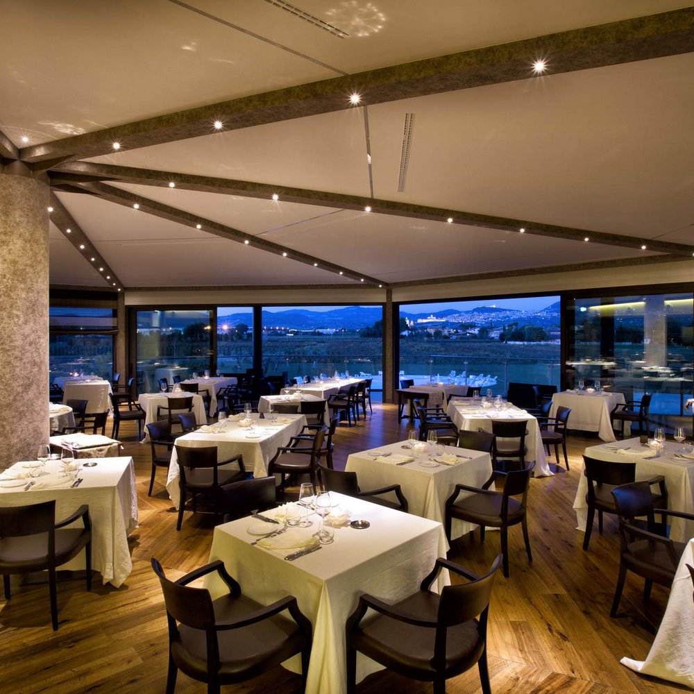 Ponte dell'Immacolata a Valle di Assisi Ristorante elegante con tavoli apparecchiati e vista panoramica serale.