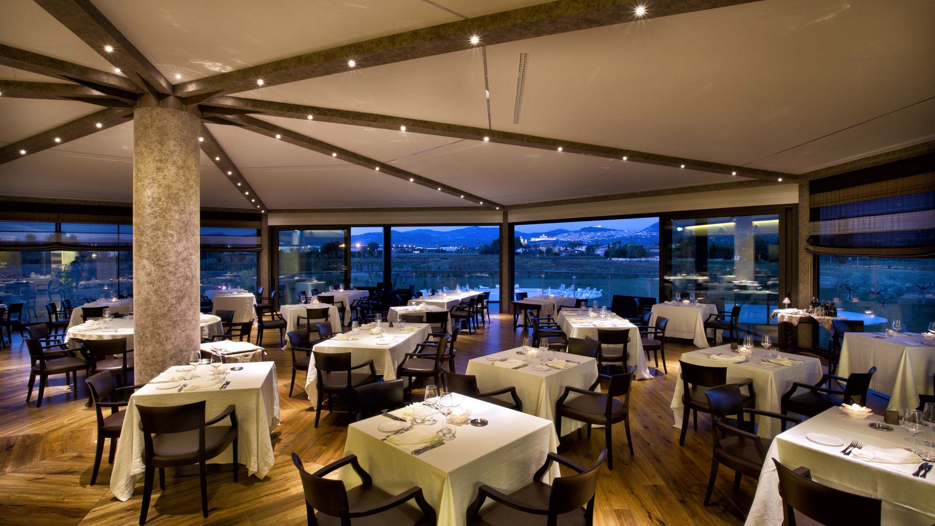 A holiday near Assisi: activities galore Elegant restaurant with set tables and evening panoramic view.