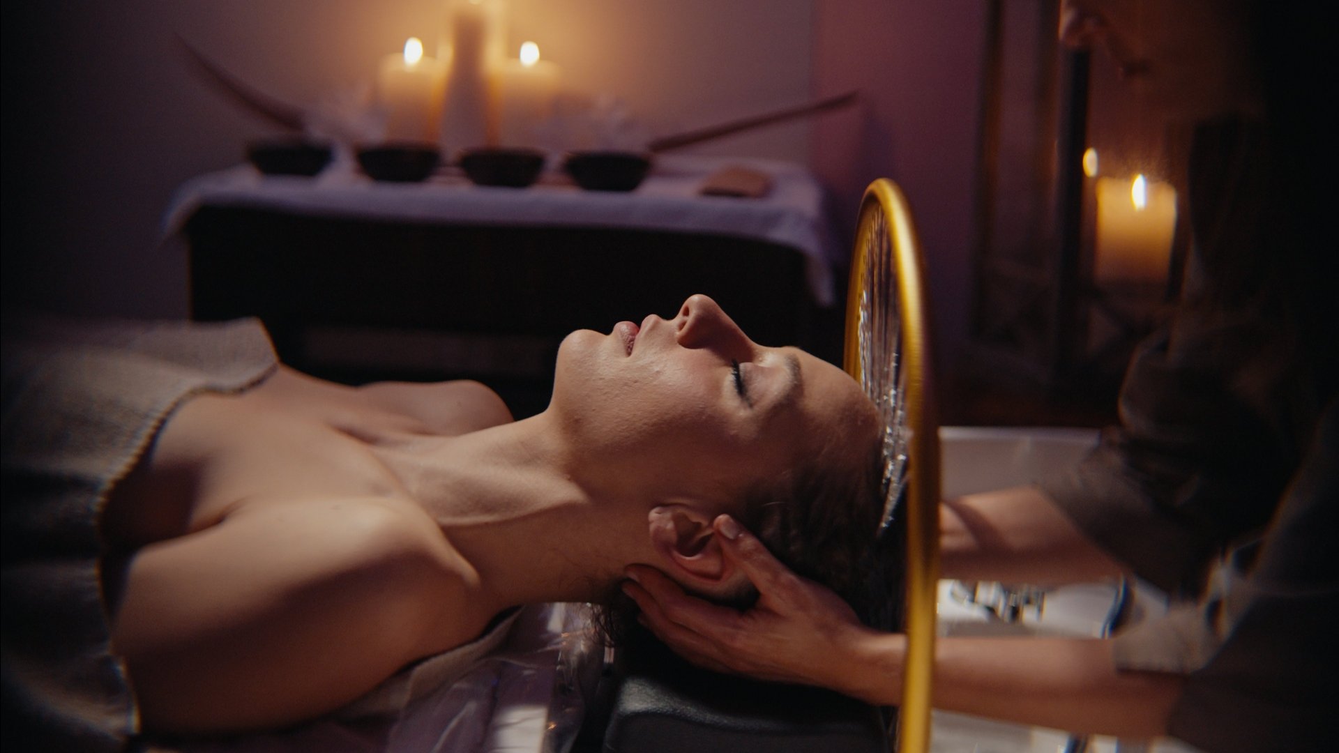 Gift Voucher Idee Regalo Festa della Mamma e anniversari dalla SPA benessere ai massaggi con cena. Donna che riceve massaggio rilassante alla testa in ambiente con candele