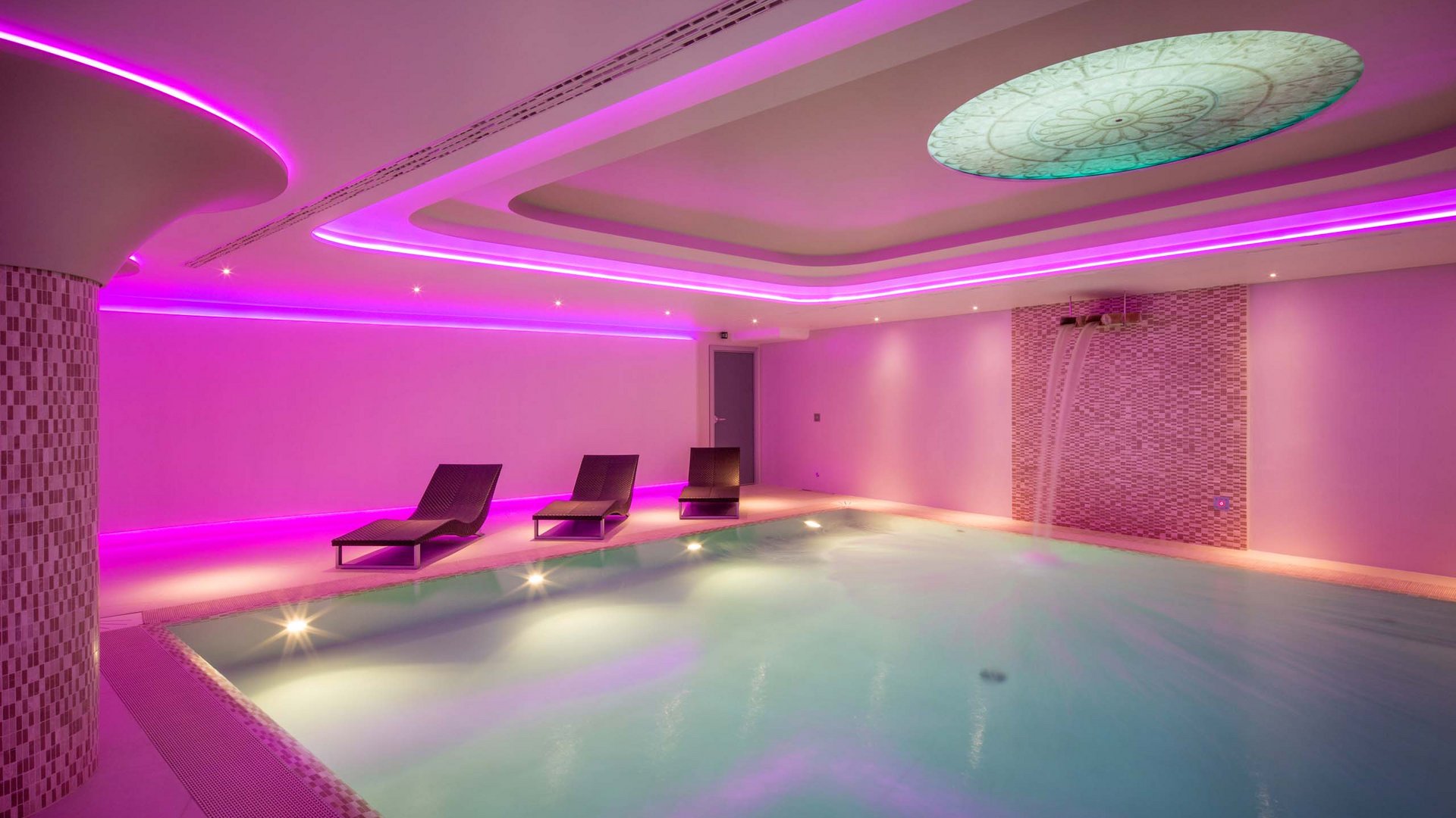 A holiday near Assisi: activities galore Indoor pool with purple lighting and three lounge chairs