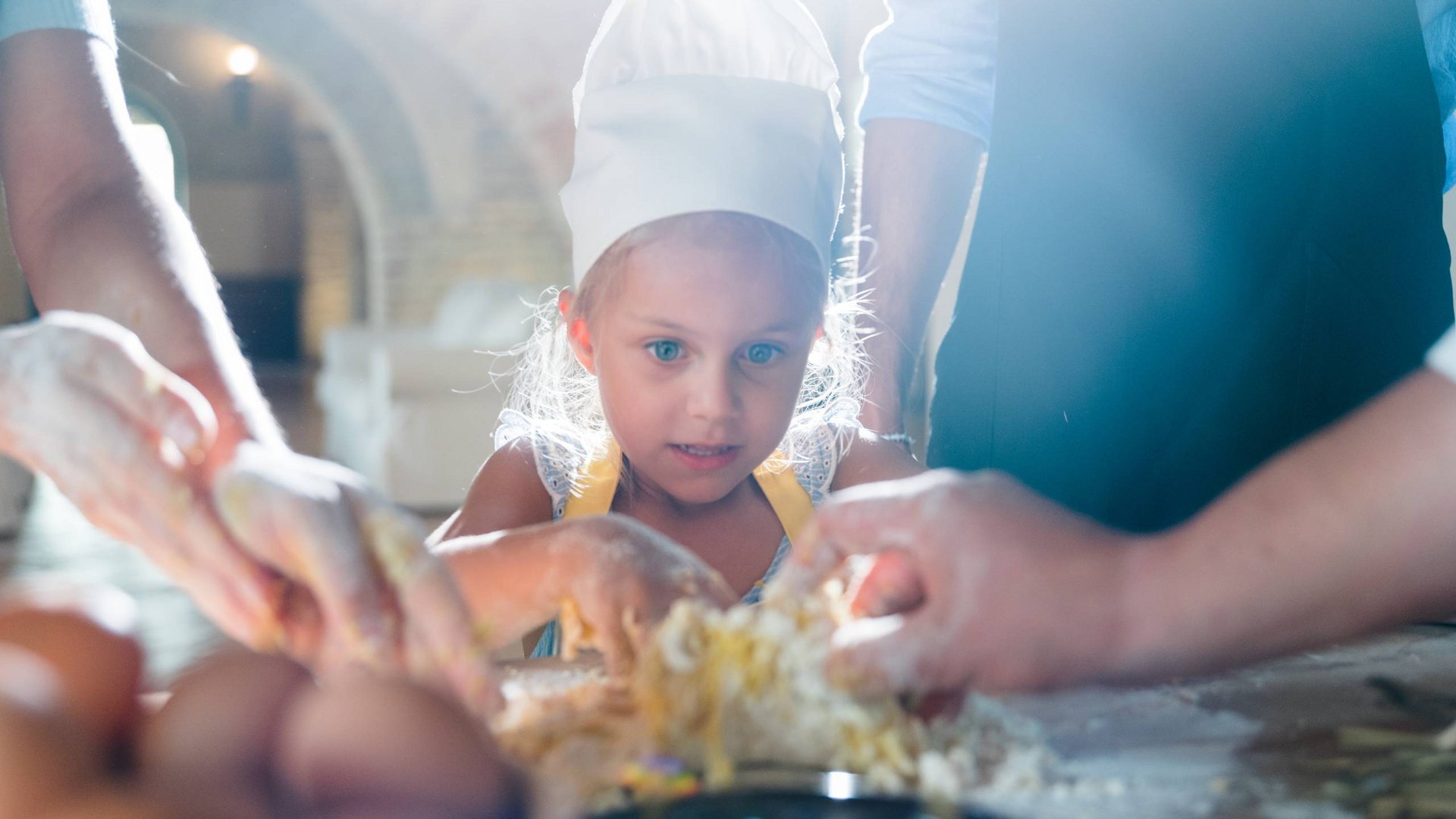 Family resort vicino ad Assisi con un ristorante da sogno Bambina con cappello da chef impasta con gli adulti in cucina