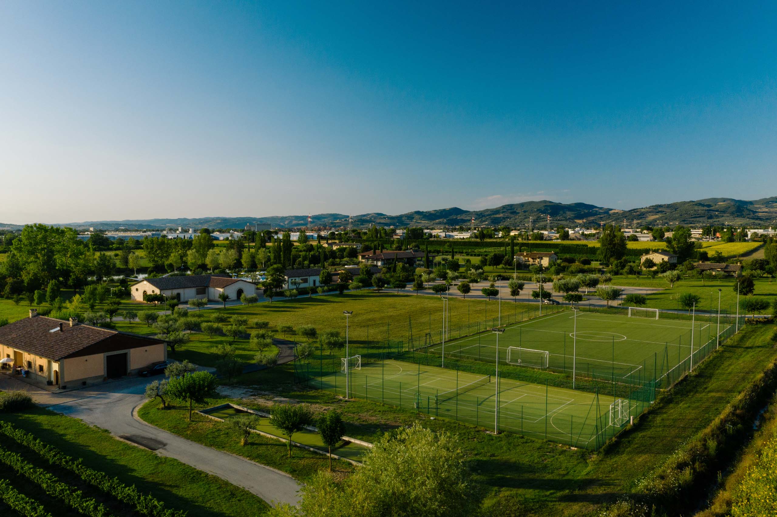 The mission of Valle di Assisi Sports fields in green area with mountains in the background